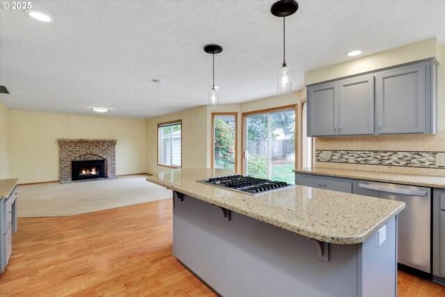 kitchen featuring a kitchen island, a breakfast bar, light wood-style flooring, gray cabinetry, and stainless steel appliances