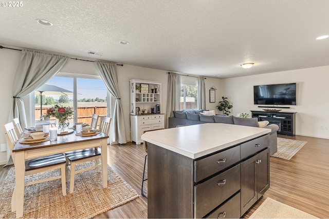 12810 NE 118th Way, Vancouver, WA 98682 - kitchen featuring open floor plan, light wood-style floors, a textured ceiling, dark brown cabinetry, and recessed lighting