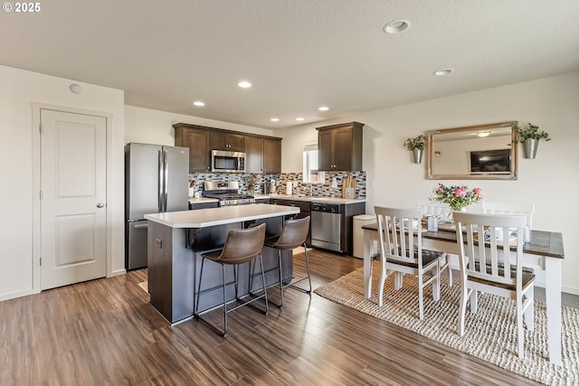 12810 NE 118th Way, Vancouver, WA 98682 - kitchen featuring appliances with stainless steel finishes, dark brown cabinets, a kitchen island, dark wood-style flooring, and light countertops