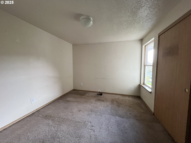 unfurnished room featuring carpet floors, baseboards, and a textured ceiling