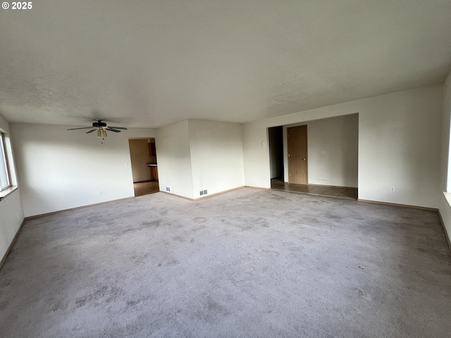 carpeted spare room with visible vents, a textured ceiling, baseboards, and a ceiling fan