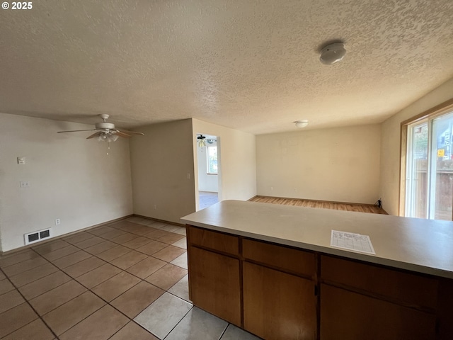 kitchen featuring light tile patterned floors, visible vents, ceiling fan, open floor plan, and light countertops