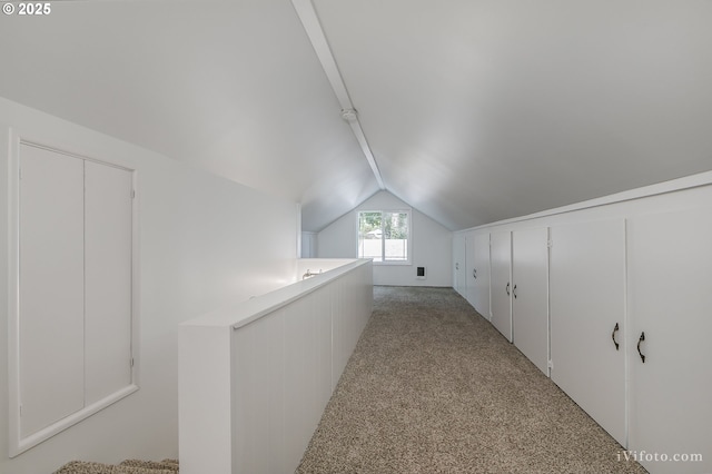 hallway with light carpet and vaulted ceiling