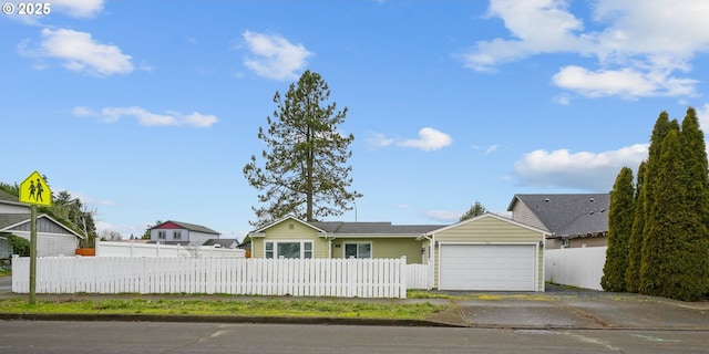 ranch-style home featuring a garage, driveway, and a fenced front yard