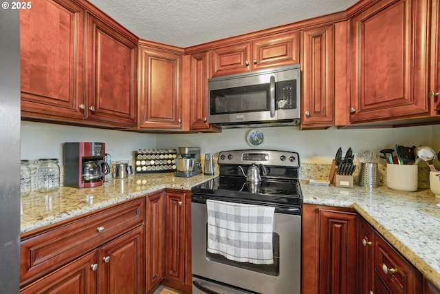 kitchen featuring appliances with stainless steel finishes, a textured ceiling, and light stone counters