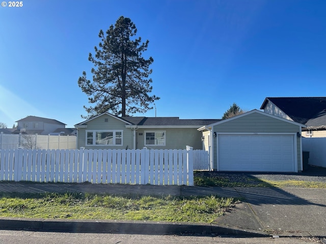 ranch-style home featuring a garage, driveway, and a fenced front yard