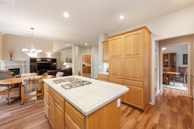 kitchen with a notable chandelier, tile countertops, light hardwood / wood-style flooring, and a center island