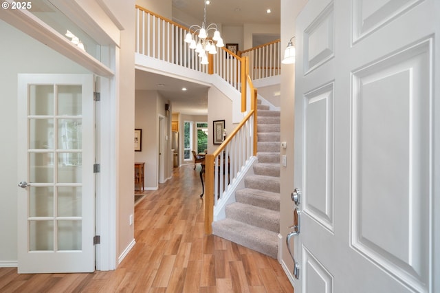 entryway featuring a chandelier, a high ceiling, and light wood-type flooring