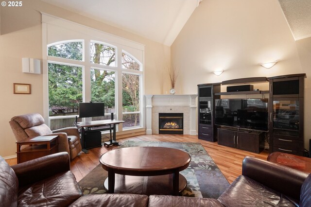 living room featuring a high end fireplace, high vaulted ceiling, and hardwood / wood-style floors