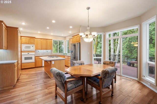 living room with high vaulted ceiling, a fireplace, a chandelier, and light hardwood / wood-style flooring