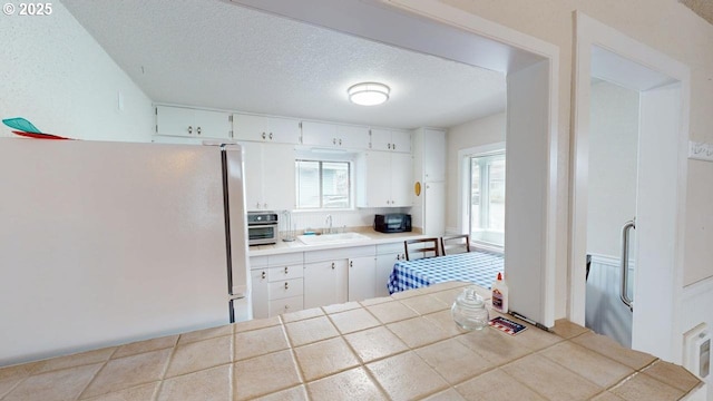 94237 6th St, Gold Beach, OR 97444 - kitchen with freestanding refrigerator, a sink, plenty of natural light, and a textured ceiling