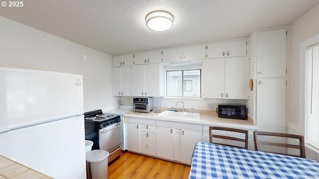 94237 6th St, Gold Beach, OR 97444 - kitchen featuring white cabinets, a sink, black microwave, range with electric stovetop, and freestanding refrigerator