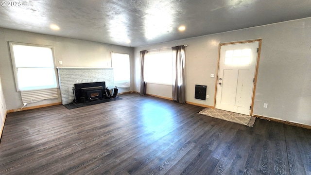 unfurnished living room featuring plenty of natural light and dark hardwood / wood-style flooring