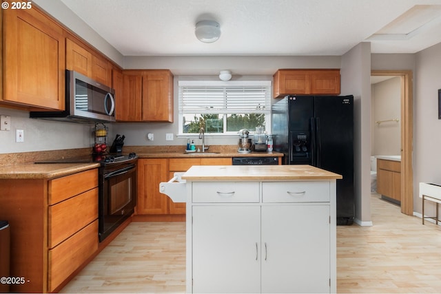 3158 SW Beach Ave, Lincoln City, OR 97367 - kitchen with black appliances, a sink, light wood finished floors, a kitchen island, and brown cabinetry