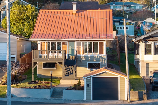 view of front facade with a garage, stairs, metal roof, and an outdoor structure