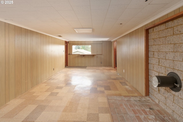 basement with crown molding, wood walls, and light floors