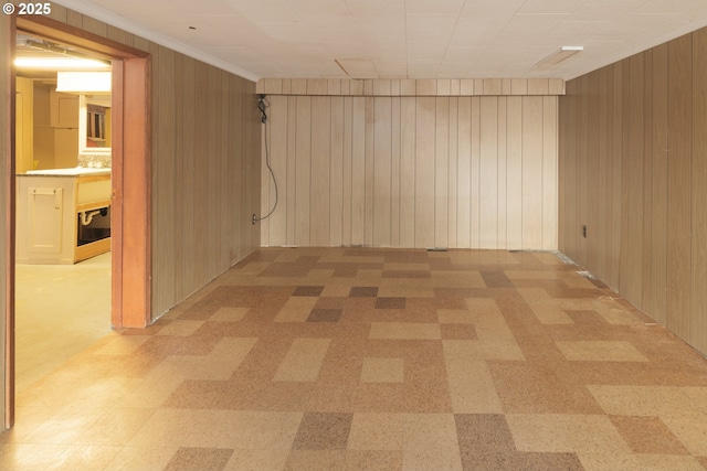 spare room with crown molding, light floors, and wooden walls