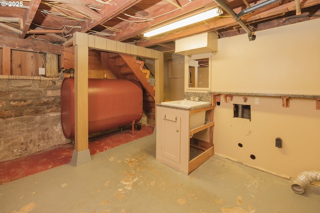 unfinished basement featuring heating fuel and stairs