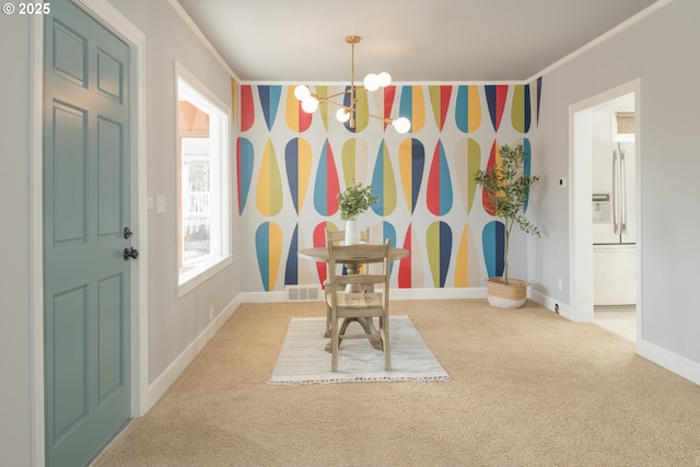 carpeted dining room featuring a notable chandelier, visible vents, ornamental molding, baseboards, and wallpapered walls