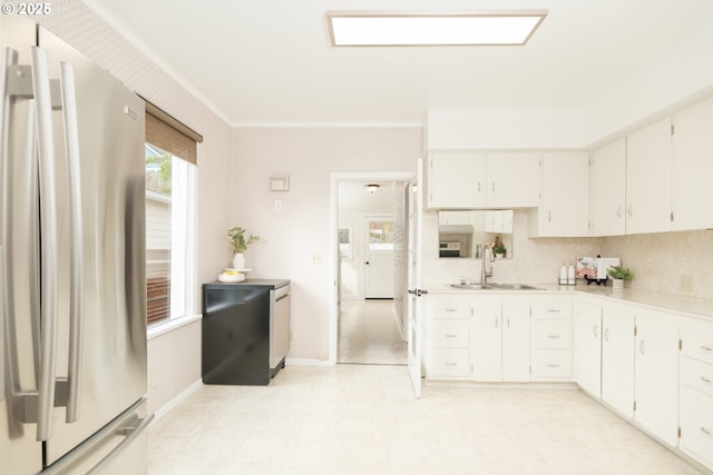 kitchen with light countertops, a sink, freestanding refrigerator, and wallpapered walls