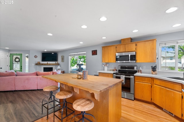 3218 SW Corbeth Ln, Troutdale, OR 97060 - kitchen with stainless steel appliances, light wood-style floors, plenty of natural light, a fireplace, and recessed lighting