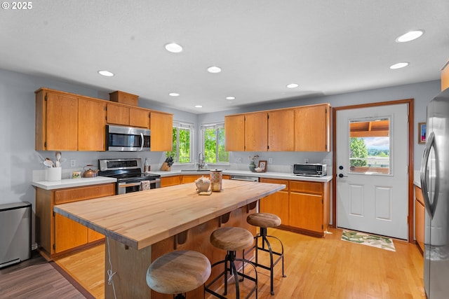 3218 SW Corbeth Ln, Troutdale, OR 97060 - kitchen featuring stainless steel appliances, light wood finished floors, wooden counters, recessed lighting, and a breakfast bar area