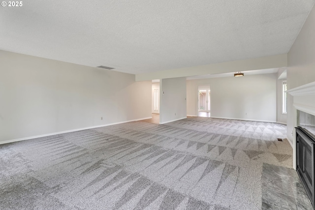 8085 SW Fairway Dr, Wilsonville, OR 97070 - unfurnished living room featuring carpet floors, a textured ceiling, a fireplace with flush hearth, and healthy amount of natural light