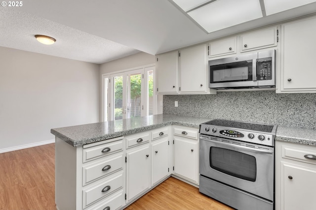 8085 SW Fairway Dr, Wilsonville, OR 97070 - kitchen featuring appliances with stainless steel finishes, a peninsula, light wood-style floors, and backsplash