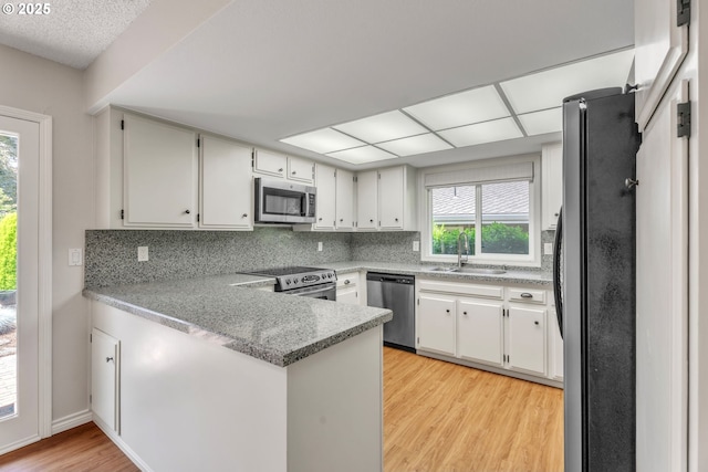 8085 SW Fairway Dr, Wilsonville, OR 97070 - kitchen featuring appliances with stainless steel finishes, a peninsula, light wood-style flooring, backsplash, and white cabinetry