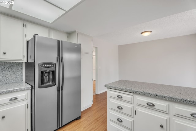 8085 SW Fairway Dr, Wilsonville, OR 97070 - kitchen featuring stainless steel fridge with ice dispenser, light wood finished floors, white cabinets, and light stone counters