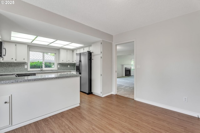 8085 SW Fairway Dr, Wilsonville, OR 97070 - kitchen featuring stainless steel fridge with ice dispenser, white cabinets, light wood-style flooring, tasteful backsplash, and light stone countertops