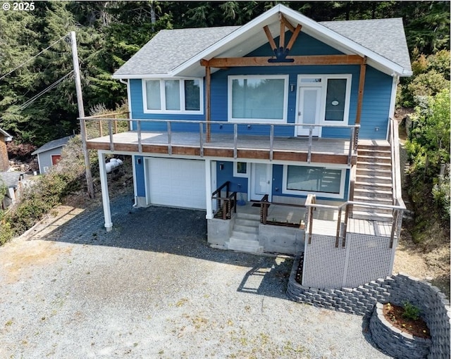 view of front facade with roof with shingles, stairs, a porch, and gravel driveway