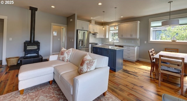 living room featuring baseboards, a wood stove, recessed lighting, and light wood-style flooring