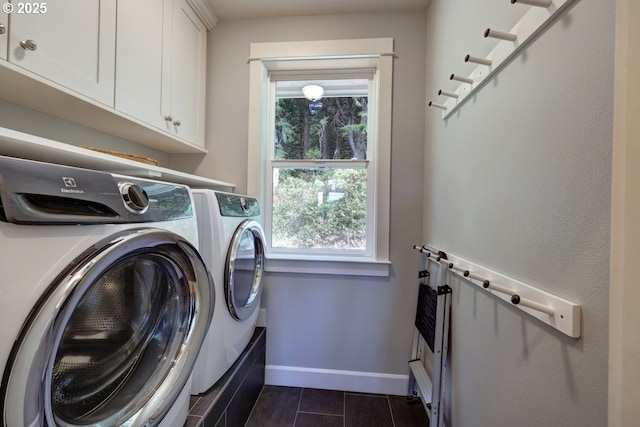 washroom featuring dark tile patterned floors, baseboards, cabinet space, and washer and dryer