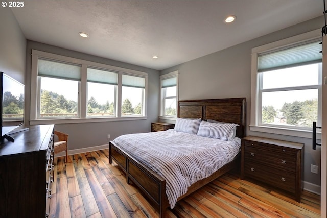 bedroom with recessed lighting, baseboards, and light wood-style flooring