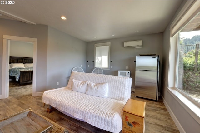 living area with recessed lighting, baseboards, light wood finished floors, and a wall mounted air conditioner