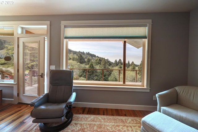 living area featuring baseboards, a healthy amount of sunlight, and wood finished floors