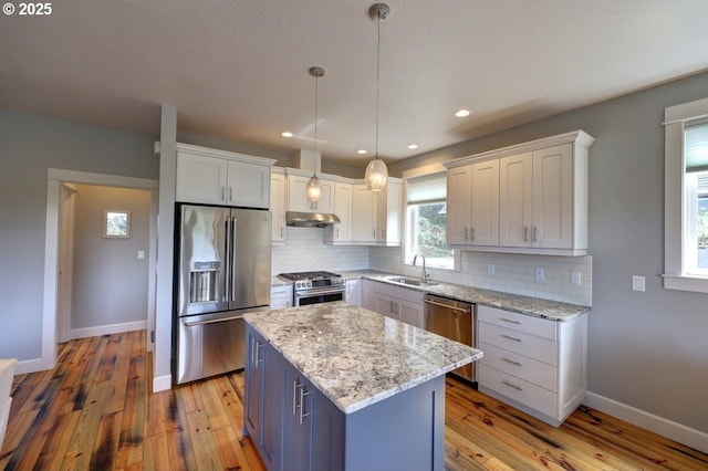 kitchen featuring stainless steel appliances, decorative backsplash, a sink, and light wood-style floors