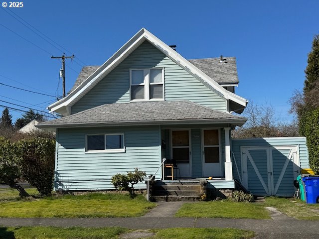 back of house with a storage shed, a porch, an outdoor structure, and a shingled roof