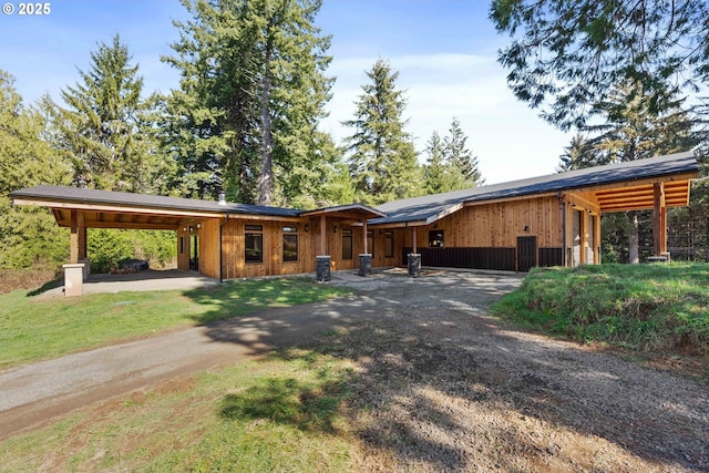 view of front facade with dirt driveway and a carport