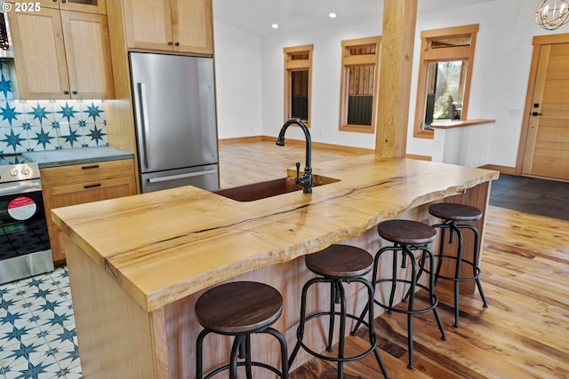 kitchen featuring a sink, appliances with stainless steel finishes, wood counters, and decorative backsplash