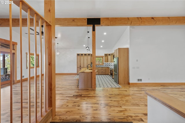 empty room with high vaulted ceiling, a sink, visible vents, light wood-style floors, and beam ceiling