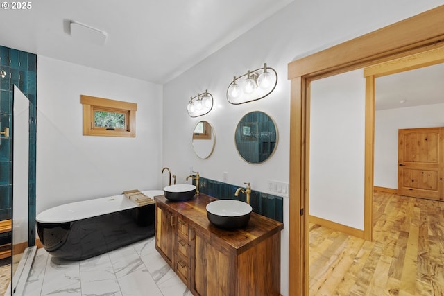 bathroom featuring a soaking tub, an enclosed shower, baseboards, and a sink