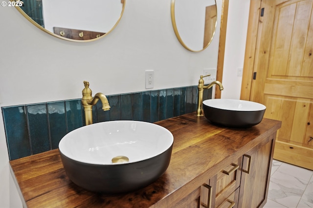 bathroom with double vanity, marble finish floor, a sink, and wainscoting