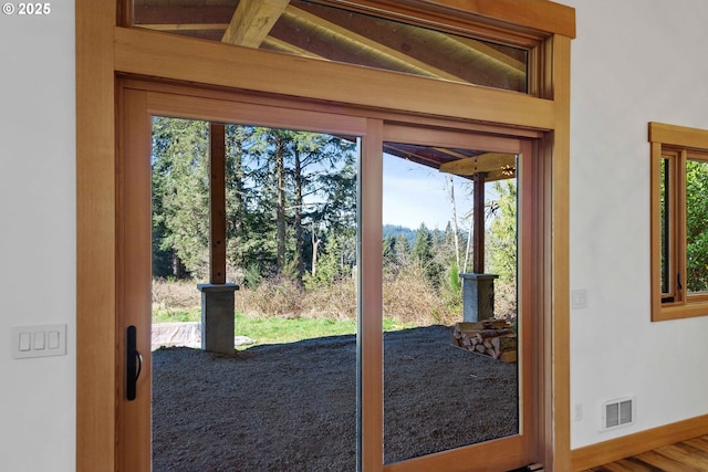 doorway to outside with a wealth of natural light, visible vents, baseboards, and wood finished floors