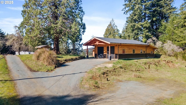 view of front of home with aphalt driveway, a detached garage, and an outdoor structure