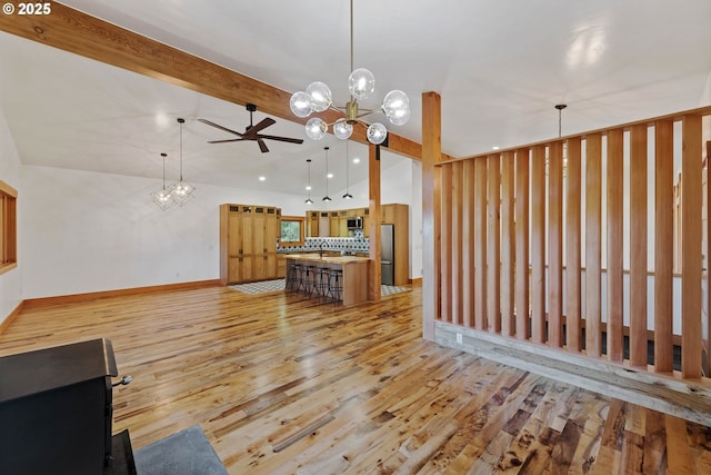 interior space with lofted ceiling with beams, light wood-style flooring, appliances with stainless steel finishes, decorative light fixtures, and backsplash