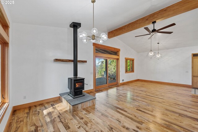 unfurnished living room featuring light wood-style flooring, a wood stove, lofted ceiling with beams, and baseboards