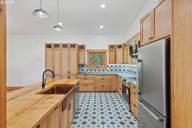 kitchen with light brown cabinets, appliances with stainless steel finishes, a sink, and decorative backsplash