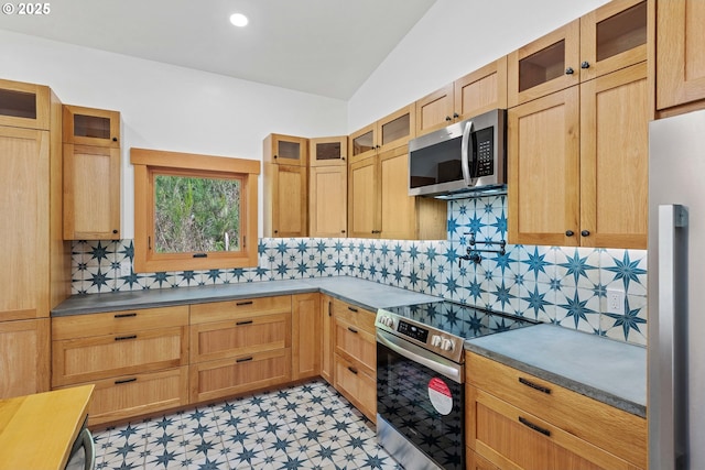 kitchen featuring stainless steel appliances, glass insert cabinets, vaulted ceiling, and tasteful backsplash